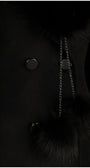 Close-up of Lucy Wool Coat with Fur Collar in Black showcasing buttons and fur pom-pom detail on chain accessory
