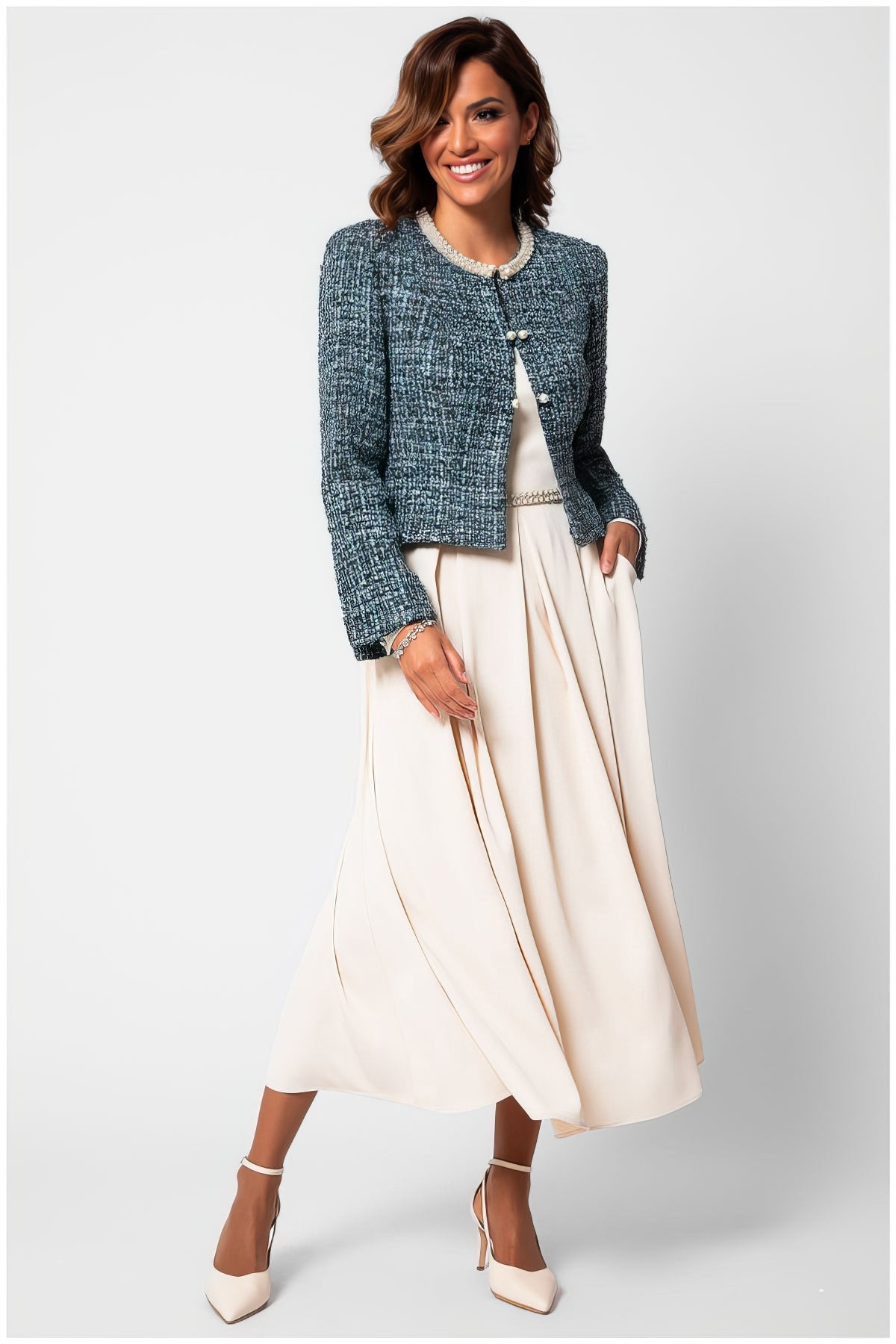 Woman wearing Rhea Tweed Blazer with Pearl Trim in Turquoise Black styled with a flowing cream dress and heels