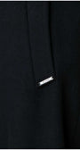 Close-up detail of Nicole Wool Wrap Coat in Solid Black featuring Luna brand metal tag on wool fabric