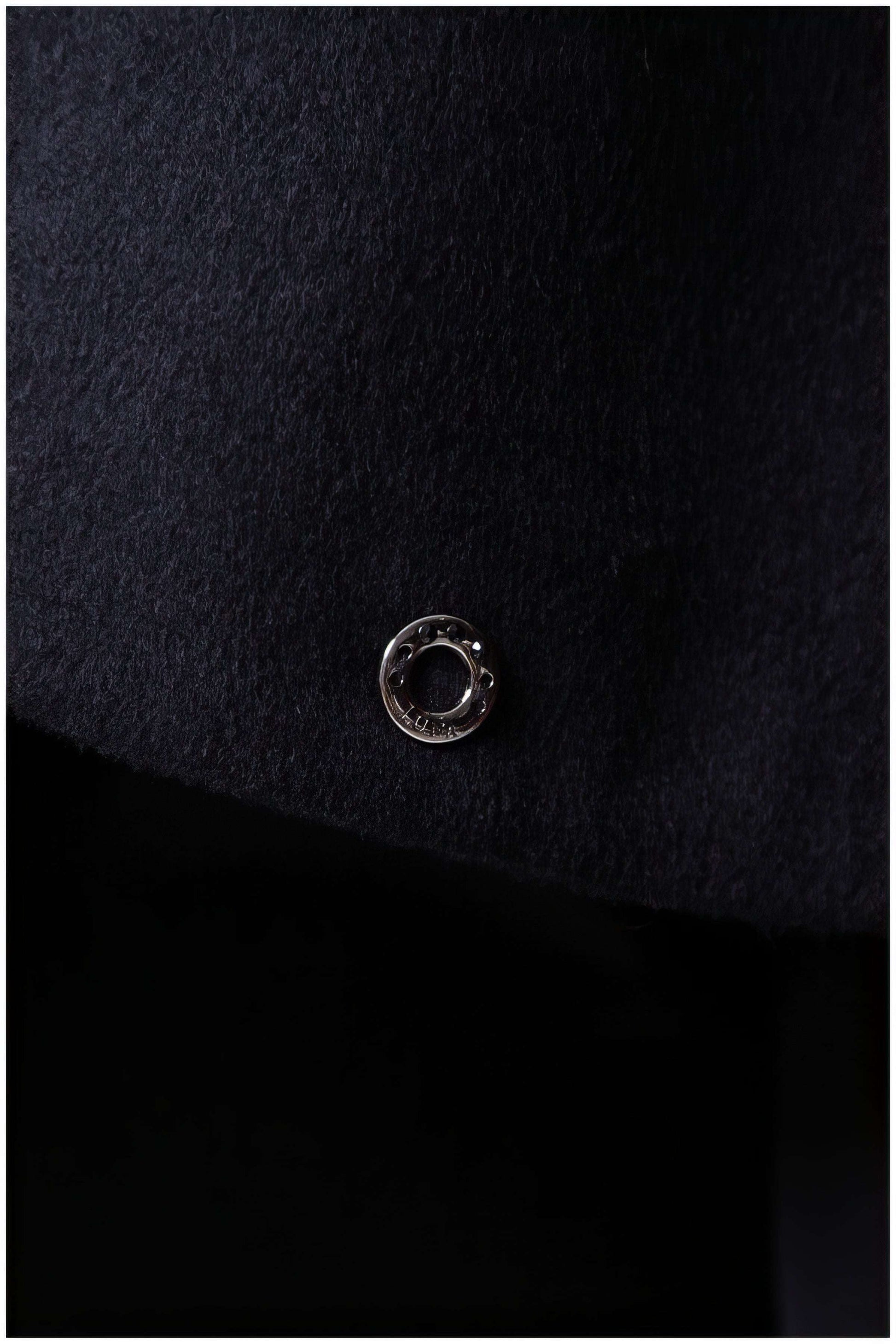 Close-up detail of the metal accent on the Selina Wool Cape in Black showcasing quality craftsmanship and texture.