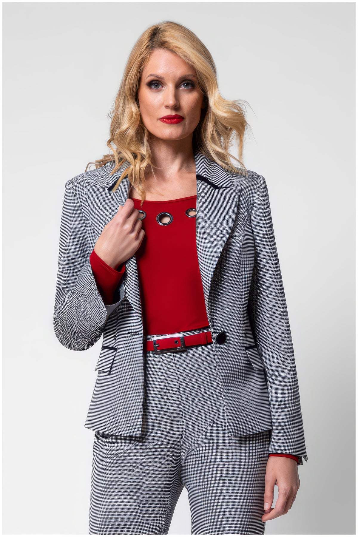 Woman wearing Elena Houndstooth Tailored Blazer with matching pants and red top, showcasing elegant tailored fit.