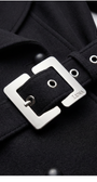 Close-up of a black coat with a silver belt buckle featuring the brand 'LUNA'.