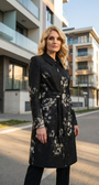 Woman wearing a black coat with a floral pattern standing on a street.