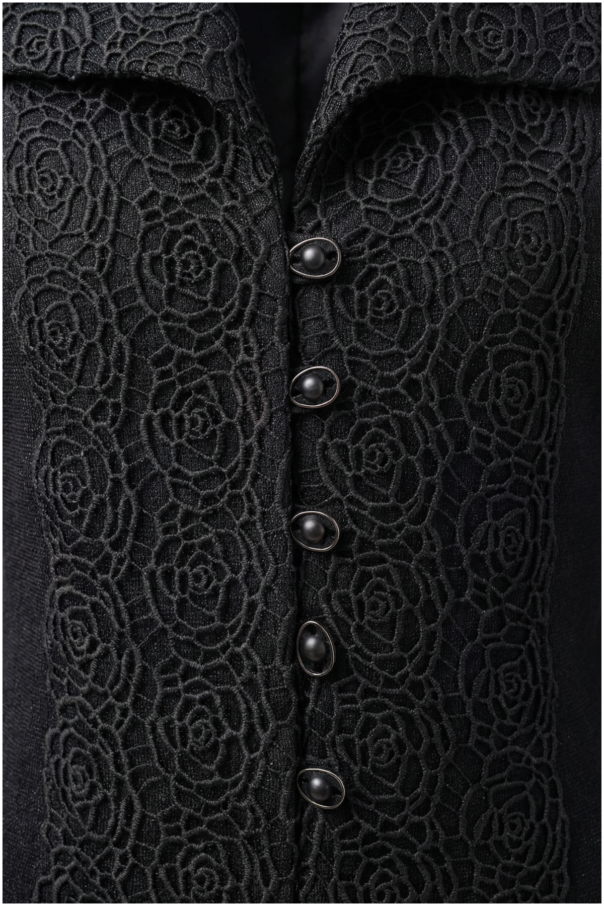 Close-up of a black textured garment with floral patterns and buttons.