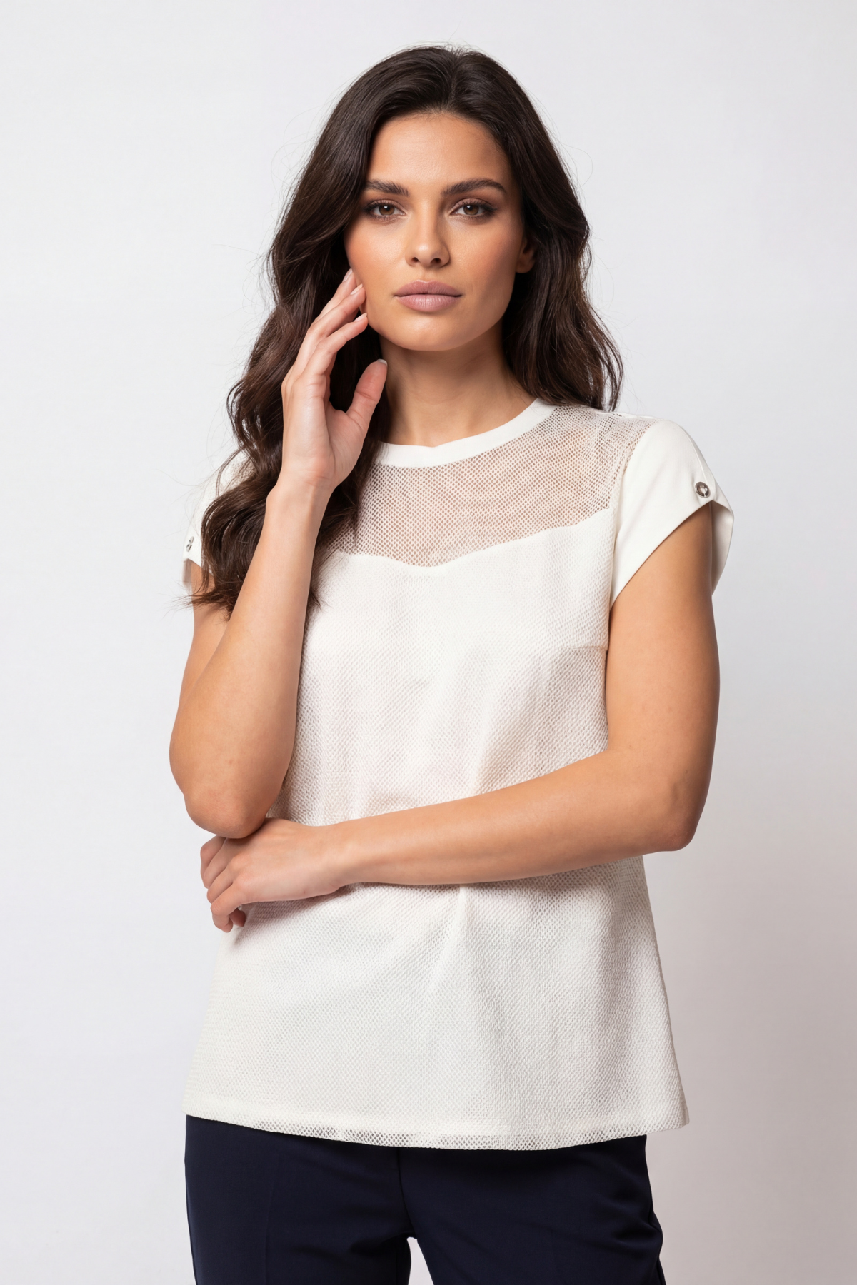 Woman wearing a white blouse with sheer sleeves against a plain background