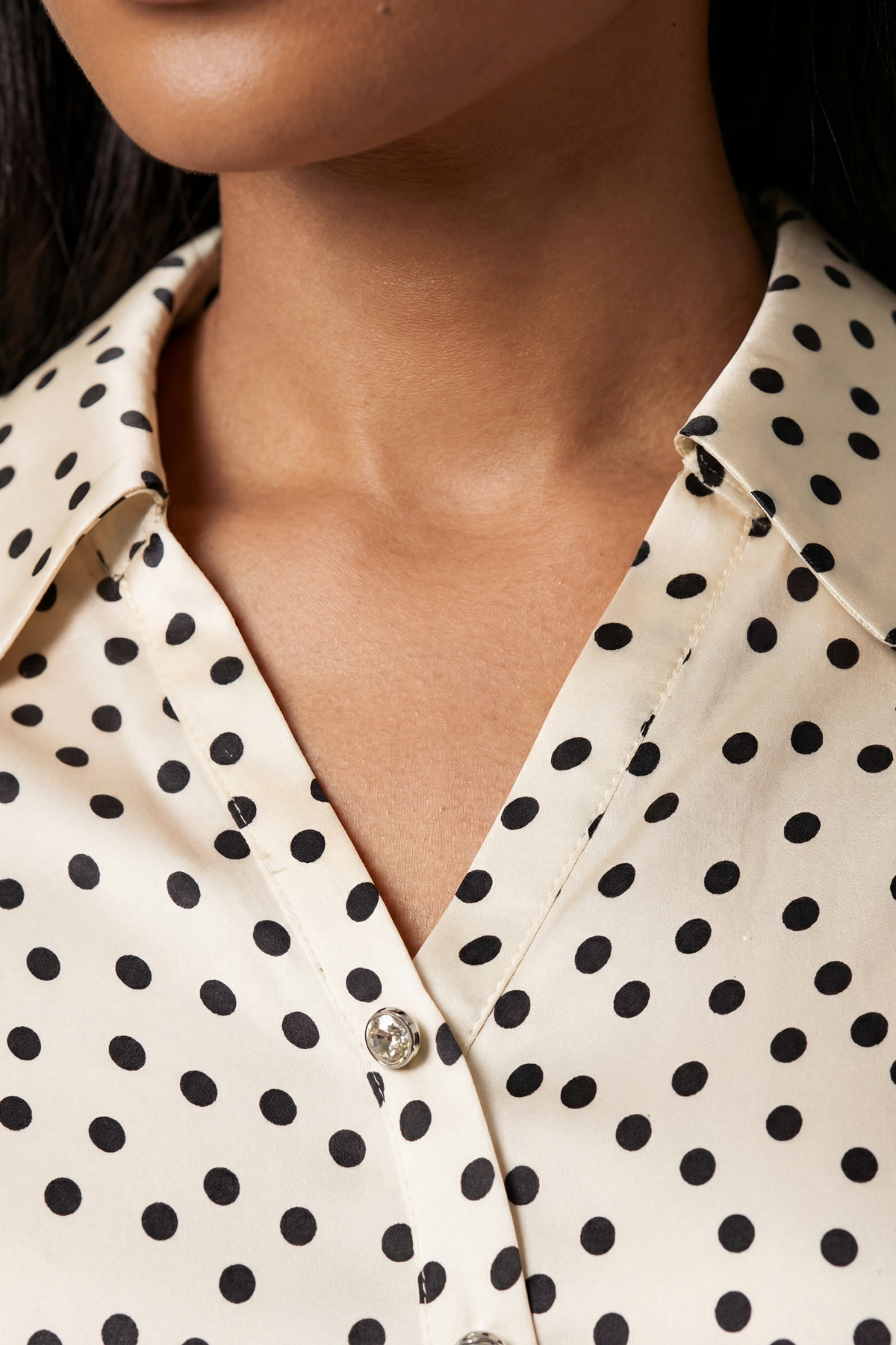 Close-up of a person wearing a polka dot shirt with a neutral background