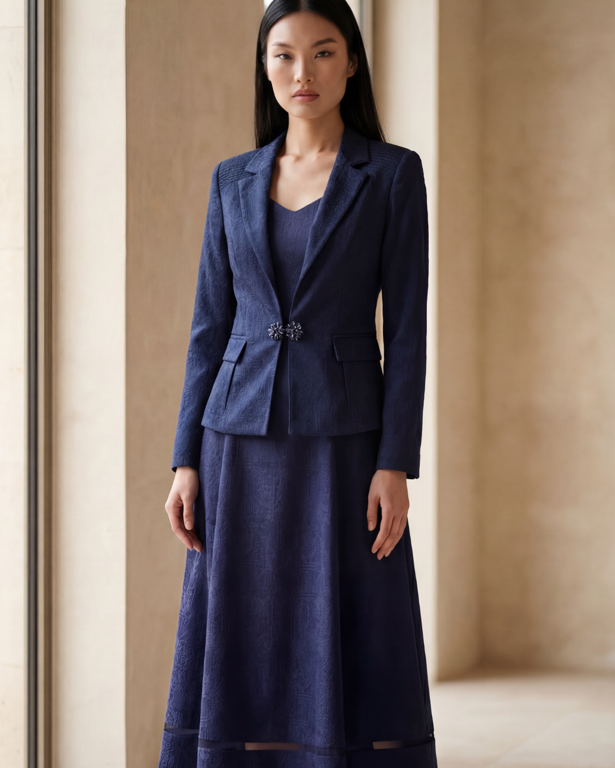 Woman wearing a blue suit standing in a room with large windows.