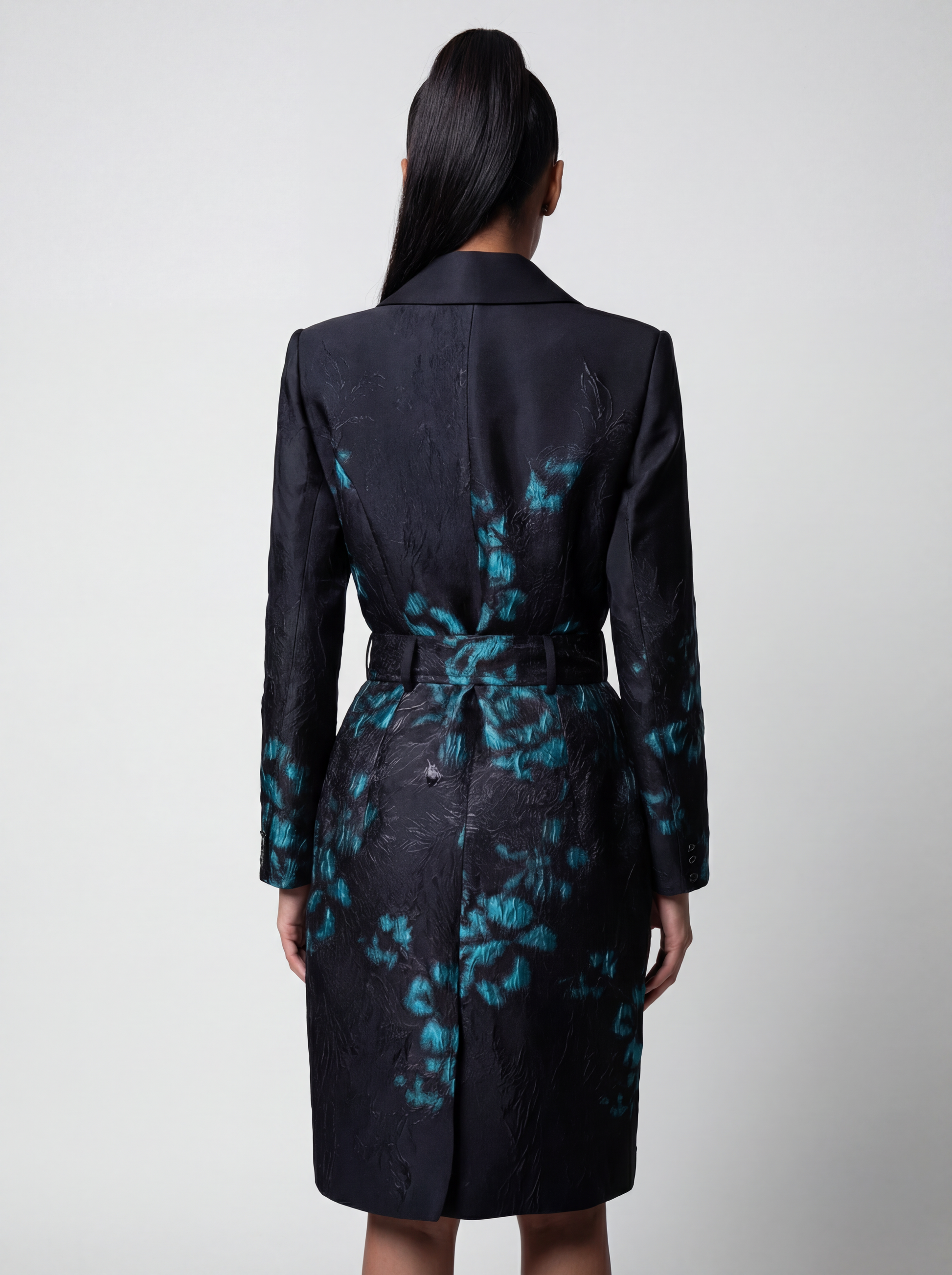 Woman wearing a black coat with blue floral patterns on a white background