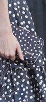 Woman in black polka dot A-line midi dress for French-inspired garden party, Betty Luna Fashion House